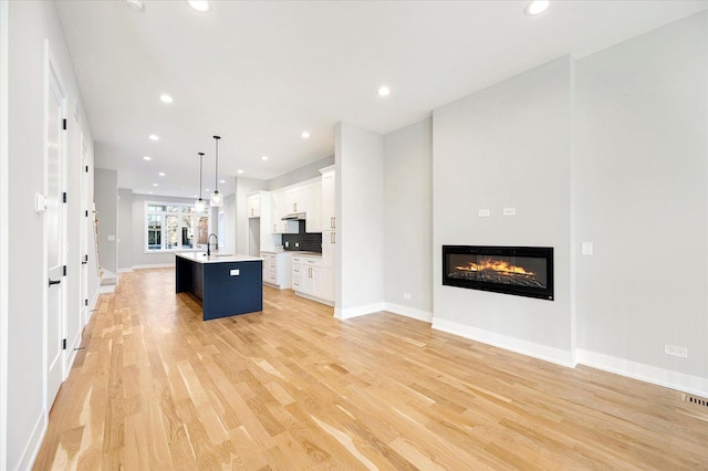 3502 S Union Ave, Chicago, IL 60609 - kitchen featuring a sink, light wood-type flooring, open floor plan, white cabinetry, and a kitchen island with sink