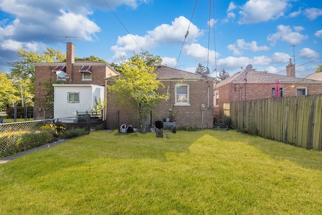 rear view of property with brick siding, a fenced backyard, and a lawn