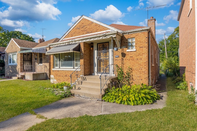 bungalow featuring brick siding, a chimney, and a front yard