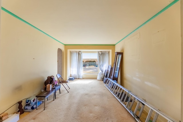 hallway featuring arched walkways, carpet flooring, and crown molding