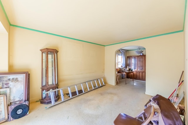 living area featuring arched walkways, carpet flooring, and crown molding
