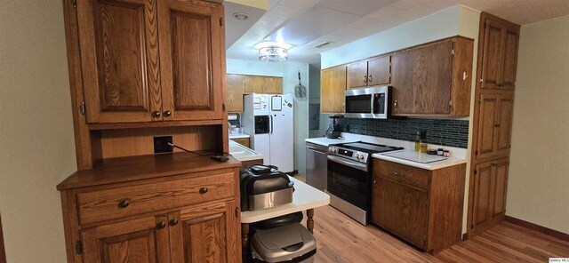 508 N Fayette, Carthage, IL 62321 - kitchen featuring appliances with stainless steel finishes, tasteful backsplash, light wood-style flooring, and brown cabinets