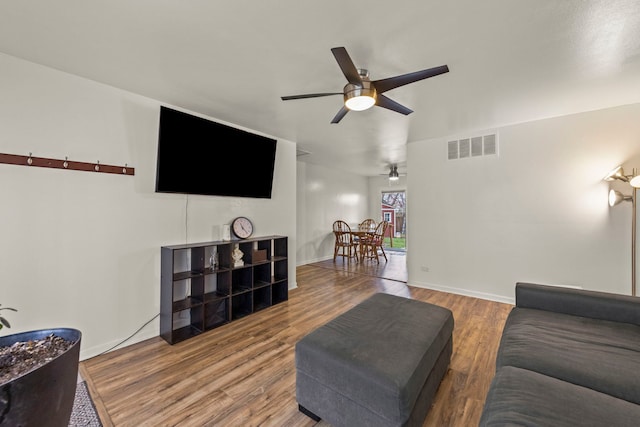 living area with visible vents, baseboards, wood finished floors, and ceiling fan