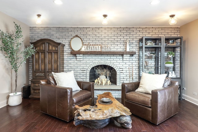 sitting room featuring baseboards, a brick fireplace, and hardwood / wood-style floors
