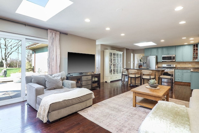 living room featuring a skylight, recessed lighting, and dark wood finished floors