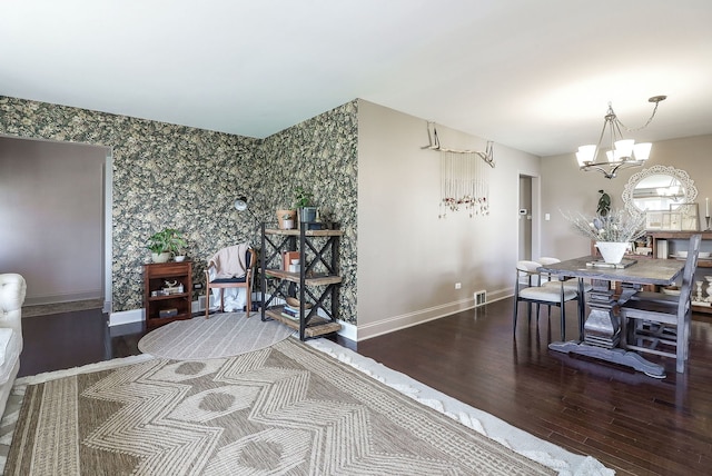 dining space featuring an accent wall, wood finished floors, wallpapered walls, an inviting chandelier, and baseboards