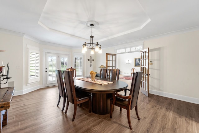 dining area featuring a raised ceiling, baseboards, french doors, and wood finished floors