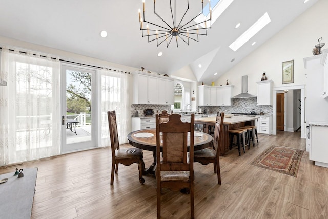 dining space with recessed lighting, light wood finished floors, high vaulted ceiling, and a skylight