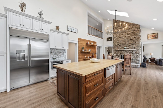 kitchen with stainless steel appliances, butcher block counters, an inviting chandelier, a warming drawer, and light wood-style floors