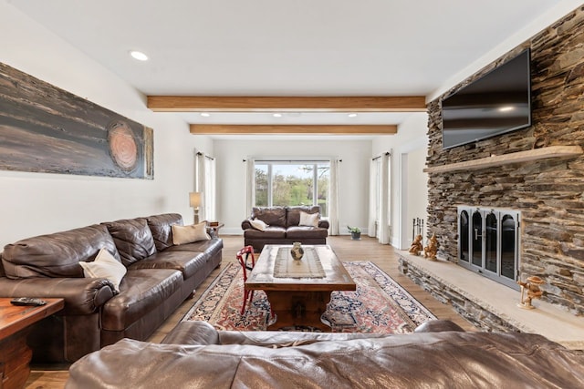 living area featuring recessed lighting, baseboards, a stone fireplace, wood finished floors, and beam ceiling