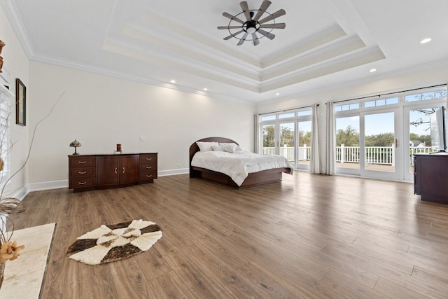 bedroom featuring a raised ceiling, access to outside, multiple windows, and wood finished floors