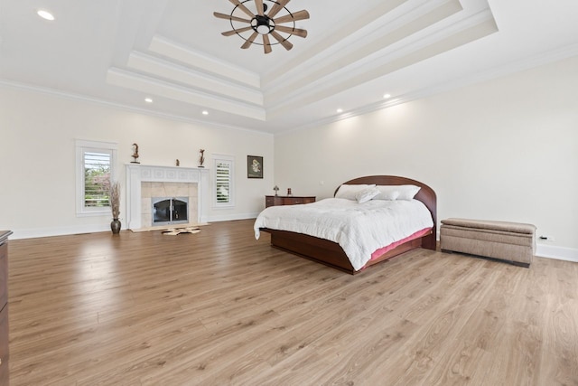bedroom with light wood-style flooring, a raised ceiling, and ornamental molding