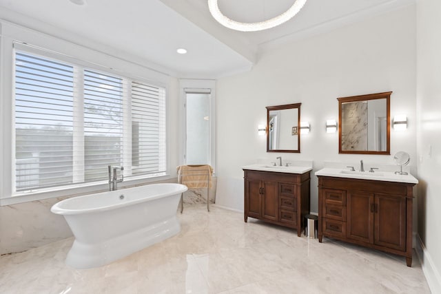 full bathroom with a sink, a freestanding bath, plenty of natural light, and marble finish floor