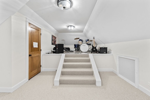 stairway featuring lofted ceiling, baseboards, and carpet floors
