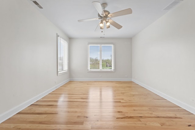 spare room with ceiling fan, baseboards, light wood-type flooring, and visible vents
