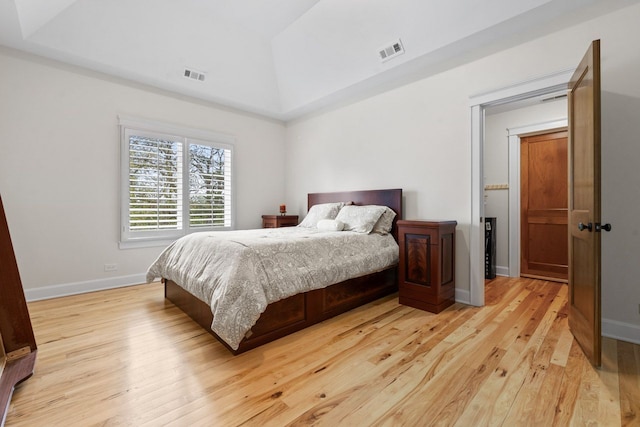 bedroom featuring light wood-type flooring, visible vents, baseboards, and lofted ceiling