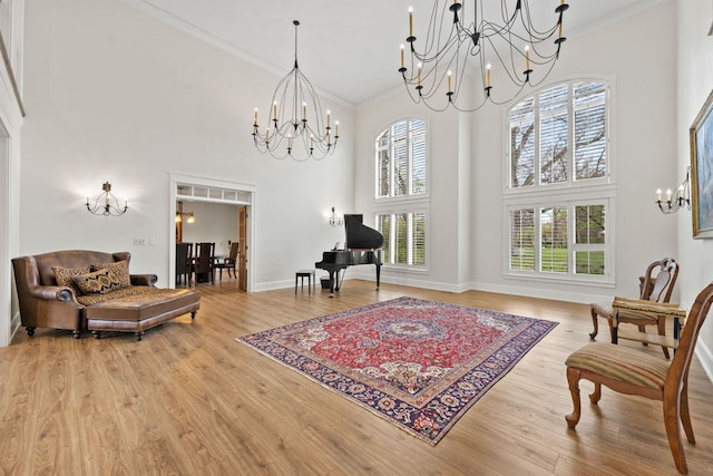 sitting room featuring a notable chandelier, crown molding, a towering ceiling, and wood finished floors