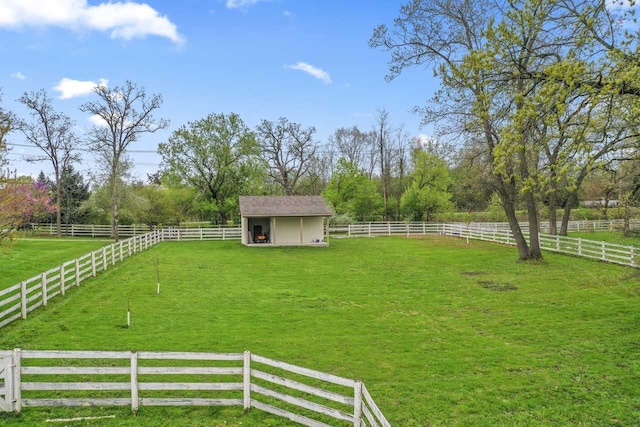 view of yard with fence, a rural view, and an outbuilding