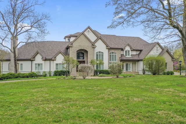 french provincial home featuring stucco siding and a front lawn