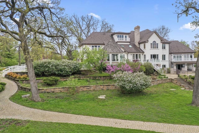 rear view of house with fence, a chimney, a lawn, and stairs