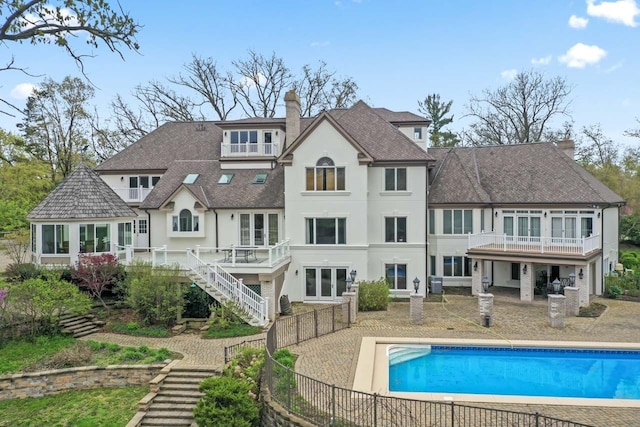 rear view of property featuring a patio area, stairs, stucco siding, a fenced backyard, and a chimney