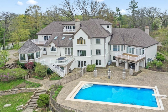 rear view of house featuring a chimney, stairs, a wooden deck, and a fenced in pool