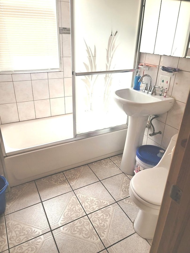 bathroom featuring tile patterned floors, toilet, a healthy amount of sunlight, and tile walls