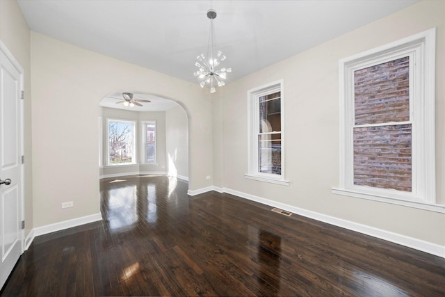 unfurnished dining area with arched walkways, a chandelier, baseboards, and dark wood-style flooring