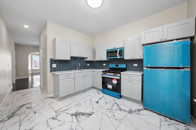 kitchen with a sink, decorative backsplash, marble finish floor, and stainless steel appliances