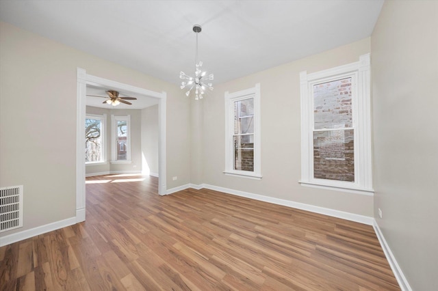 empty room with visible vents, baseboards, an inviting chandelier, and light wood finished floors