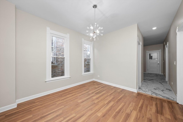 unfurnished dining area featuring recessed lighting, baseboards, an inviting chandelier, and light wood finished floors
