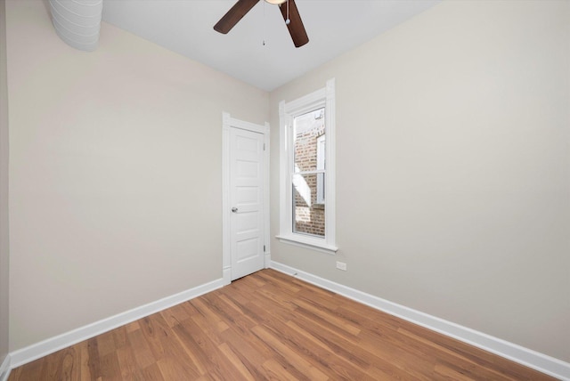 empty room with baseboards, a ceiling fan, and light wood finished floors