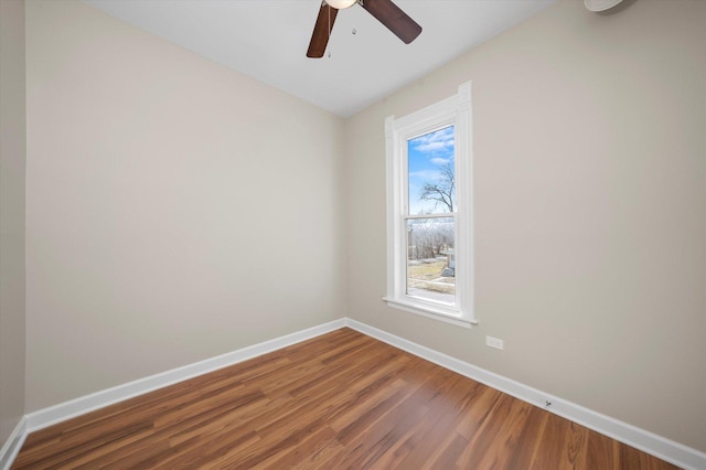 unfurnished room with a ceiling fan, wood finished floors, and baseboards