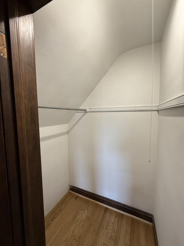 walk in closet with wood finished floors and vaulted ceiling