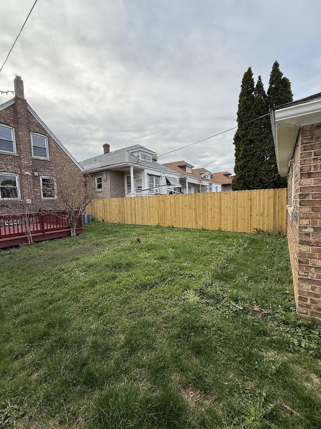view of yard with central AC unit, fence, and a deck