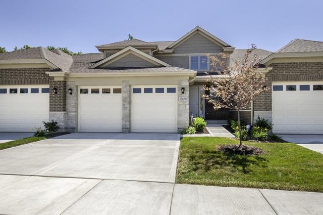 view of front of house with brick siding, stone siding, an attached garage, and driveway