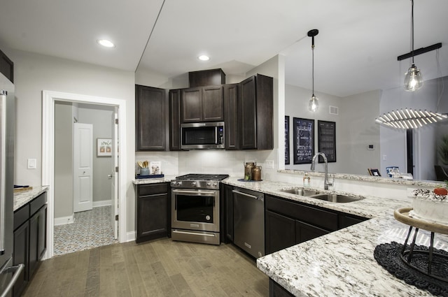 kitchen with backsplash, light stone countertops, stainless steel appliances, and a sink