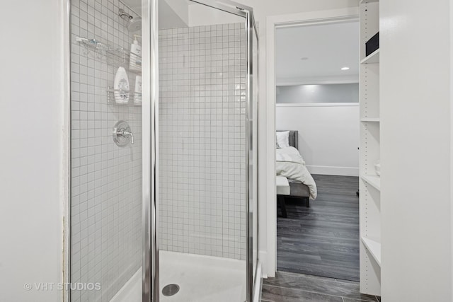 bathroom featuring connected bathroom, wood finished floors, and a stall shower