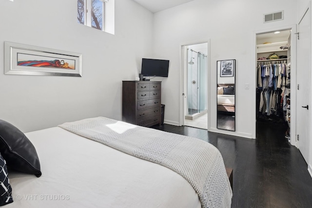 bedroom featuring a spacious closet, connected bathroom, dark wood-style floors, visible vents, and a closet