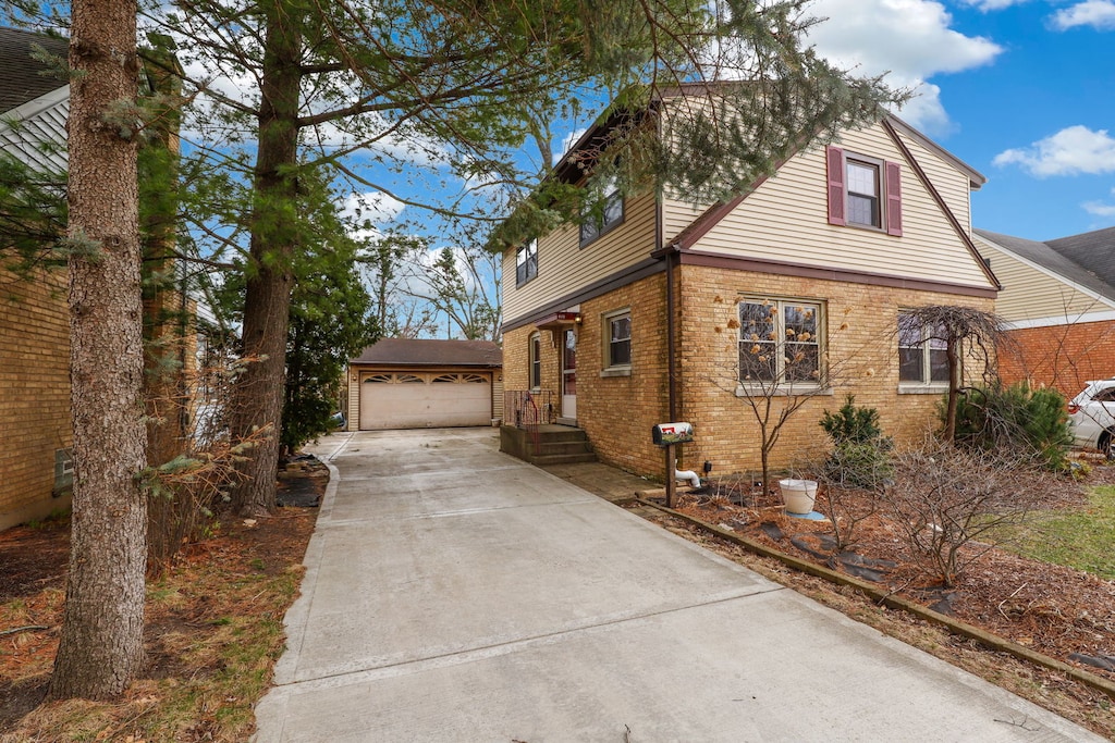 view of front of property with an outdoor structure, brick siding, driveway, and a garage