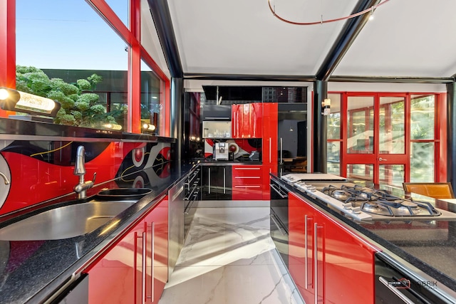 kitchen with marble finish floor, a sink, dark countertops, stainless steel gas stovetop, and dishwashing machine