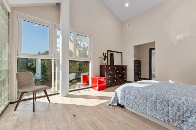 bedroom featuring wood finished floors, visible vents, and high vaulted ceiling