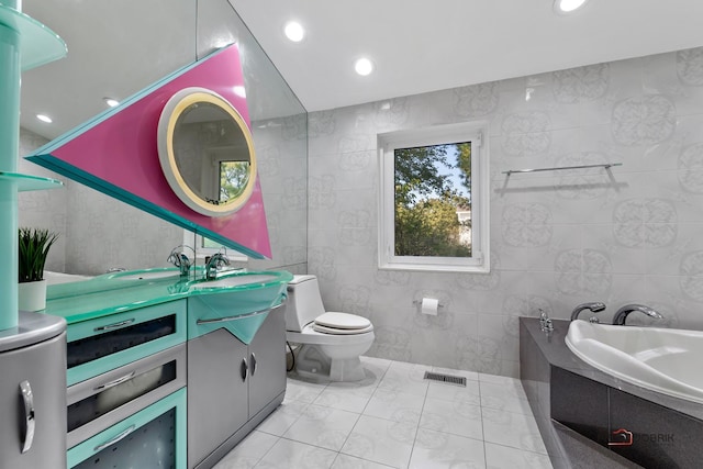 full bath featuring vanity, visible vents, tiled tub, tile walls, and toilet