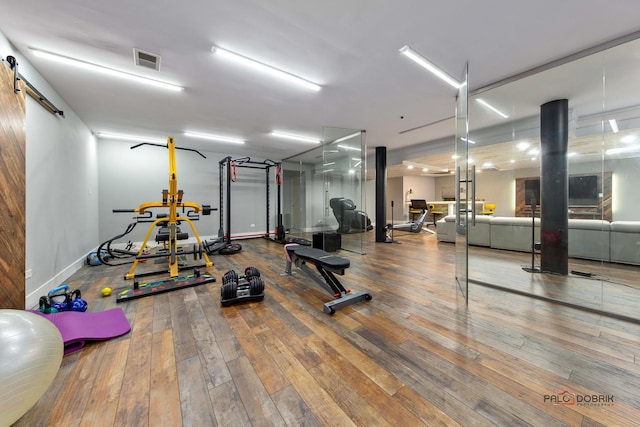 gym featuring visible vents, a barn door, and wood-type flooring