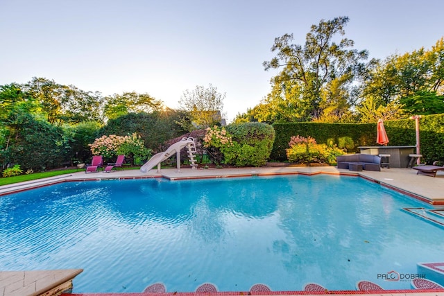 view of pool with a patio area, a fenced in pool, and a water slide