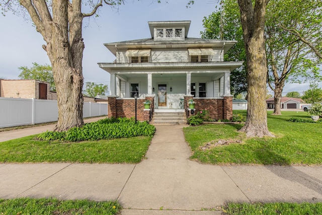american foursquare style home featuring a front yard, a porch, brick siding, and fence