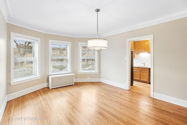 unfurnished dining area with crown molding, radiator, light wood-style flooring, a sink, and baseboards