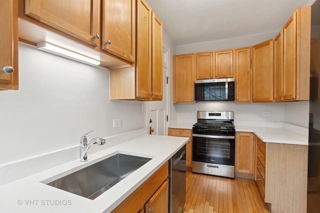 kitchen featuring light countertops, light wood-style floors, appliances with stainless steel finishes, and a sink