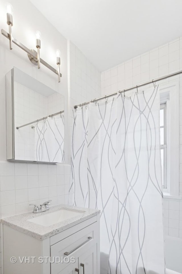 bathroom with shower / bath combo, tasteful backsplash, vanity, and tile walls