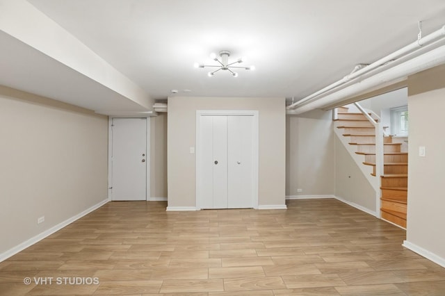 finished below grade area with stairs, light wood finished floors, and baseboards